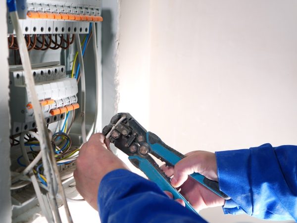 Electrician works with internet cable conneting. Electrical swit Electrician works with internet cable conneting. Electrical switchboard with automats and wires.